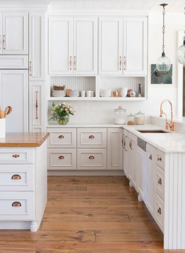 Dapur dengan lemari dapur berwarna putih dan peralatan tembaga